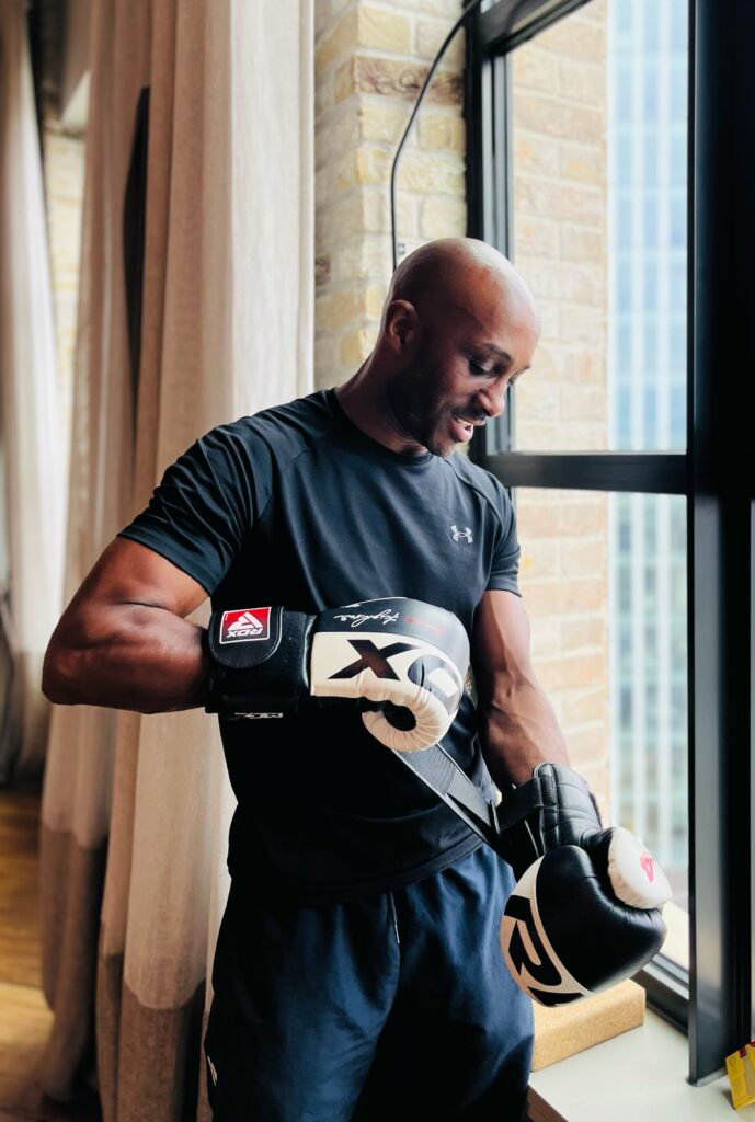 Richard Williams strapping on boxing gloves by a window